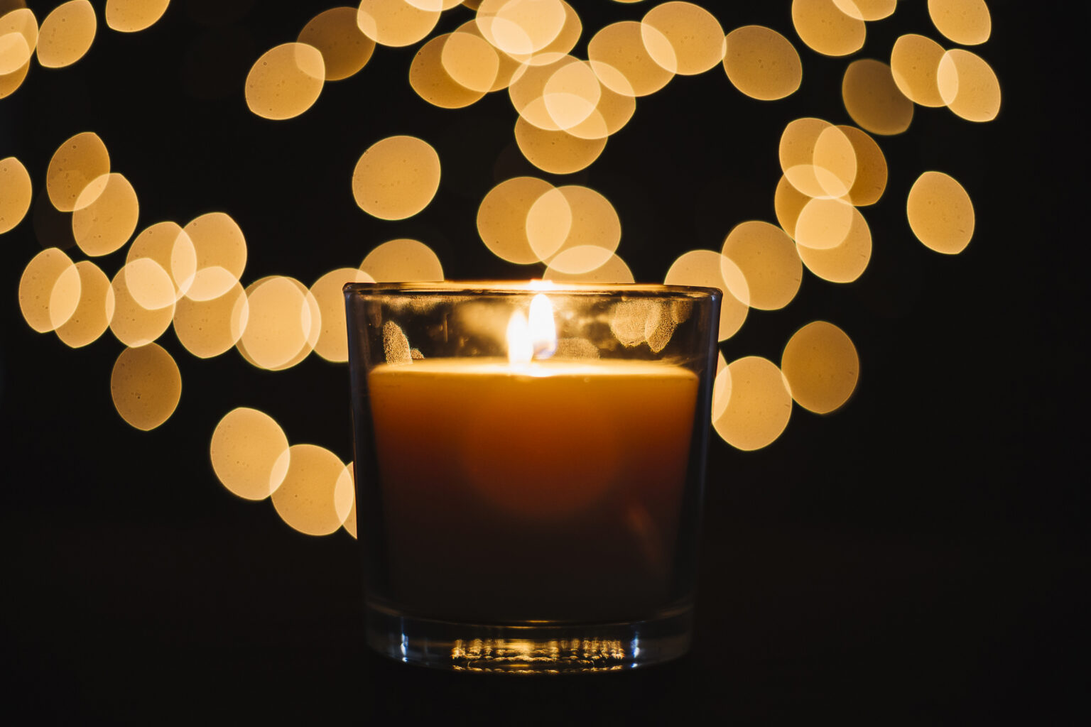 Eine angezündete Kerze mit dunklem Hintergrund